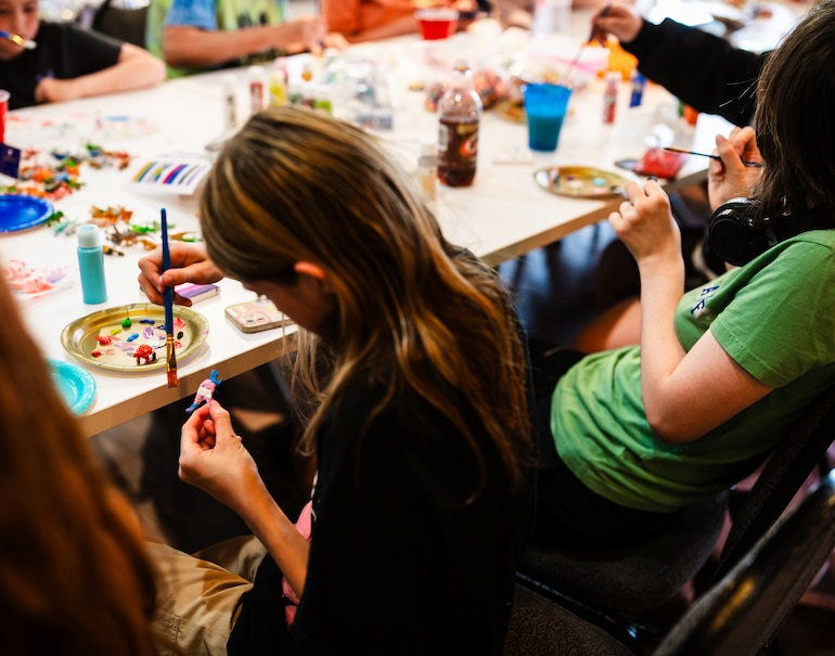 Youngster paining dinosaur with blue, purple and white during Craft Night at Clock Inc. LGBT+ Community Center in Rock Island with Free Mom Hugs