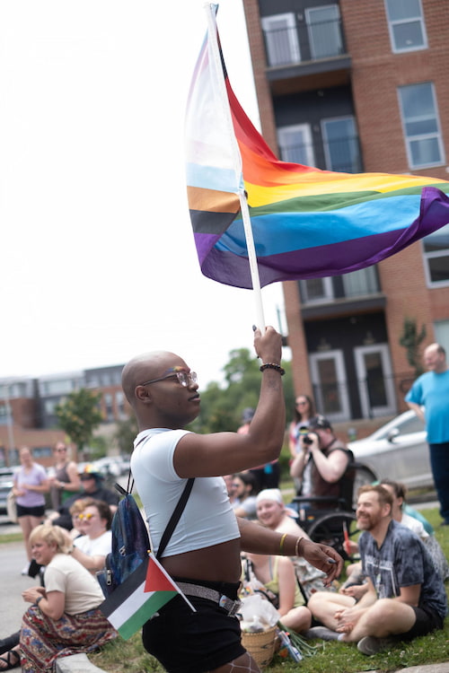 Attendee waving progress Pride flag in the Iowa City Pride Parade June 15